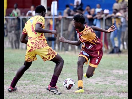 Wolmer’s Boys’ Davaughn Ricketts looks on while Denham Town’s Odeano Porteous attempts some tricks during their ISSA/WATA Manning Cup football encounter at St Andrew Technical High School on Friday.