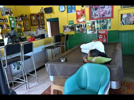 Credit: Rudolph Brown Photos A bartender takes a nap as it’s another slow day for customers in 11 Miles.