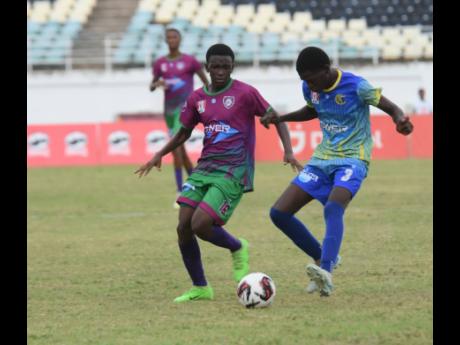 Ashley Anguin/Photographer 
Kaheel Campbell (left) of William Knibb Memorial High School competes with Denton Livingston of Cedric Titus High during their Zone D football match in the ISSA/WATA daCosta Cup competition at the Trelawny Multi-Purpose Stadium on Saturday. William Knibb won 3-0.