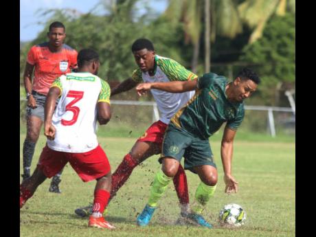 Credit: Lennox Aldred Matthew Woo Ling (right) of Vere Phoenix turns away from Humble Lion’s Jay Jameison (left) and Karim Bryan, while referee Daneon Parchment has a close look during the Jamaica Premier League football game at Wembley Centre of Excellence in Clarendon yesterday. The game ended in a 1-1 draw.