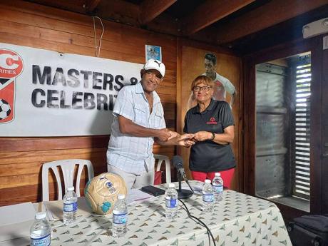 Credit: Contributed Clive ‘Busy’ Campbell (left) of Master and Celebrities receives a donation from Lorna Bell, the widow of Jackie Bell, at the media launch of the annual Bell-Ziadie Memorial Football Festival at Football Factory on Thursday.