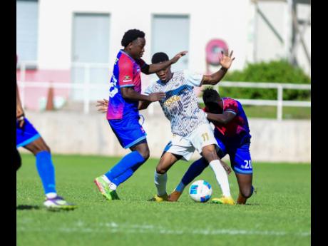 Credit: Antoine Lodge Fakibi Farquharson (left) of Dunbeholden Football Club, Christopher Ainsworth of Cavalier Soccer Club and Gerald Neil of Dunbeholden fight for possession during the Jamaica Premier League football match at Sabina Park yesterday. Cavalier won 4-1.