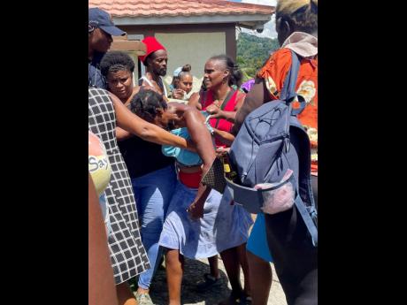 Credit: André Williams Photos A dejected Sonia Beverly (centre) is consoled by residents after her daughter’s body was found.