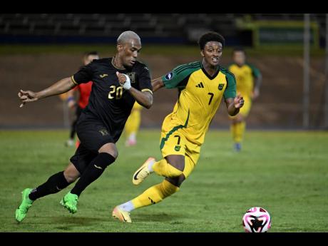 Jamaica’s Demarai Gray (right) and Honduras’ Deybi Flores chase the ball during the Concacaf Nations league football match at the National Stadium in Kingston last night. The match ended 0-0.
