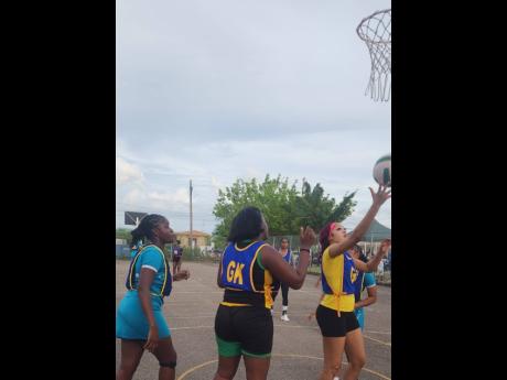 Credit: Raymond Graham Goal defence Chenika Jones of Clear Express Shipping collects a rebound as teammate, goalkeeper Suthania Scott, looks on during semi- final action in the Scrappy Nevers and Randy Williams Netball Rally at the Longsville Park Community Centre in Clarendon on Monday.