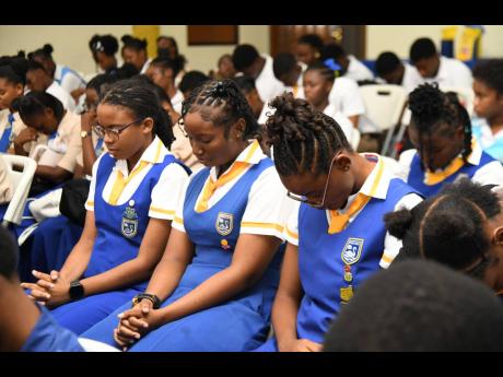 Credit: Matthew Mckoy Students of St Hugh’s High School bow their heads in prayer at the Ministry of Education’s Youth Forum, held at the Caenwood Centre, Arnold Road, Kingston, last Friday.