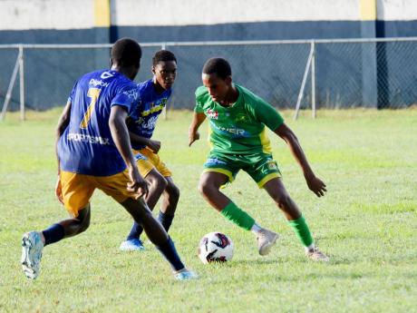 Credit: Ashley Anguin Ocho Rios High School’s Dario James Jr (right) tries to dribble past Marcus Garvey’s Rushawn Henry (left) and Norris Moodie during their ISSA/WATA daCosta Cup football match at Drax Hall Sports Complex in St. Ann on Friday, September 13.