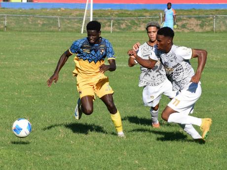Heron Headman (left) of Racing United dribbles the ball away from Cavalier Soccer Club’s Christopher Ainsworth (centre) and Kaile Auray from Cavalier during their Jamaica Premier League football match at Ferdie Neita Park yesterday. Racing United won 1-0.