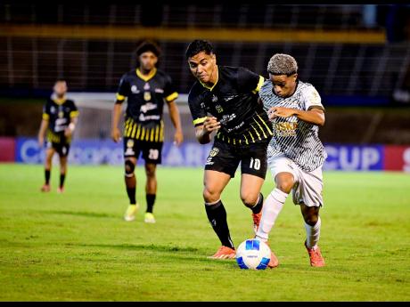 Credit: Gladstone Taylor Kaile Auvray (right) of Cavalier SC drives past Eduardo Montenegro of Moca FC during their Concacaf Caribbean Cup semi-final football match at the National Stadium in Kingston on Wednesday, October 30.