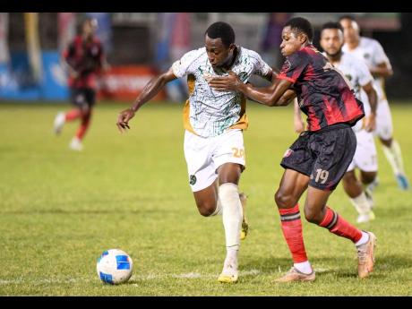Dwayne Ewen (left) of the Vere United FC pushes off Phillando Wing (right) of Arnett Gardens FC in an attempt to keep the ball during the Jamaica Premier League football match at Anthony Spaulding Sports Complex last night. Arnett won 2-0.
