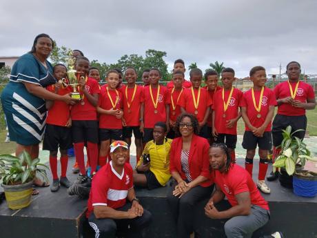 Members of the Montego Bay Preparatory football team celebrate winning the 2024 Hosanna Preparatory School 25th Anniversary Under-12 co-ed football competition on Wednesday at Hosanna Preparatory playing field. The winning trophy was presented by vice-president of the St James Football Association Deon Anglin (left). 