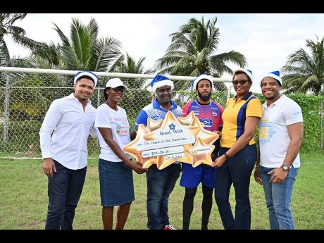 Dunbeholden FC’s manager Roger Simmonds (third left), player Shakeen Powell (third right), and Patricia Logan (second left), secretary at the Star Church of God, Dunbeholden sharing a moment with NCB Portmore’s branch manager, Joycelyn Rowe (second right), and her colleagues during the Grant-a-Wish exercise at Dunbeholen FC’s grounds.
