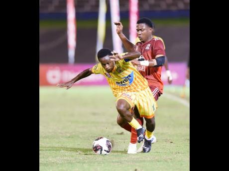 Credit: Ian Allen Photos Christopher Mundle (left) of Garvey Maceo High is tripped by Tajaun Cummings of Glenmuir High during their daCosta Cup football semi-final match at the National Stadium on Wednesday.