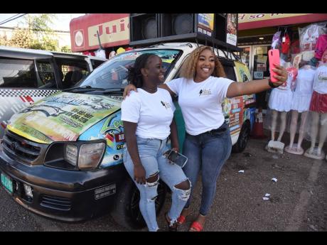 Monique ‘Moody’ Denton (right), CEO of Booze and Babez Entertainment, and an employee Tasheka ‘Petagaye’ Gilzene, who both work along with Tata Mobile Sound, take a selfie beside the ‘party bus’.