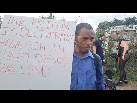 Credit: Nathaniel Stewart Godfrey Williams holds a sign proclaiming that "true freedom is deliverance from sin in Jesus Christ...," taking his message to the streets outside the National Stadium as patrons make their way into the venue for the highly anticipated Freedom Street concert on New Year's Eve.