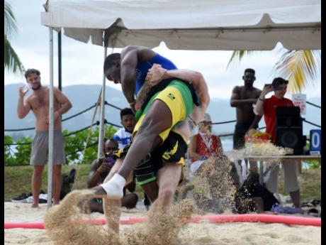 Credit: Ashley Anguin Photos Leinier Perez of Cuba (left) and Kegan Calkins from Illinois battling during the first staging of the Jamaica Wrestling Federation (JWF) Open Beach Wrestling competition at Harmony Beach Park in Montego Bay on Saturday.
