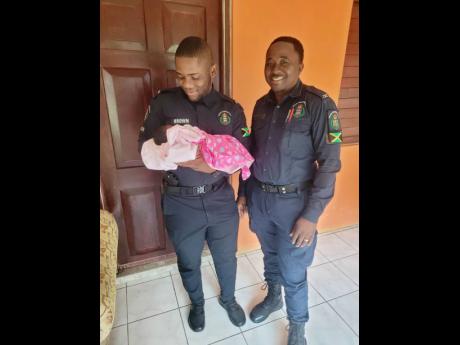 Credit: Contributed Constable Denton Brown (left) and District Constable Garey Murphy with the baby they helped deliver early Monday in St Catherine.