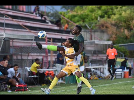 Kevaun Atkinson (right) of  Vere Phoenix kicks the ball clear of Dante Fitz of Molynes United during their Jamaica Premier League football match at the Anthony Spaulding Sports Complex yesterday. Molynes recovered from 2-0 down to win 3-2.