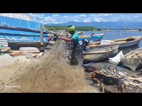 Credit: Almando Smith photos A fisherman covers himself in plastic to avoid touching the water.