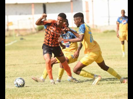 Credit: Ian Allen Roshawn Oldfield (left) of Tivoli Gardens FC is challenged for the ball by Jevoun Bascoe (centre) and Tajay Grant from Racing United during their Jamaica Premier League football match at the Edward Seaga Sports Complex yesterday.