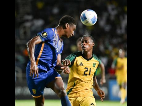 Credit: Ricardo Makyn Photos St Vincent’s defender Andrew Johnson heads the ball away while under pressure from Jamaica’s Warner Brown during the Concacaf Gold Cup Qualifier at Sabina Park yesterday. Jamaica won 3-0.