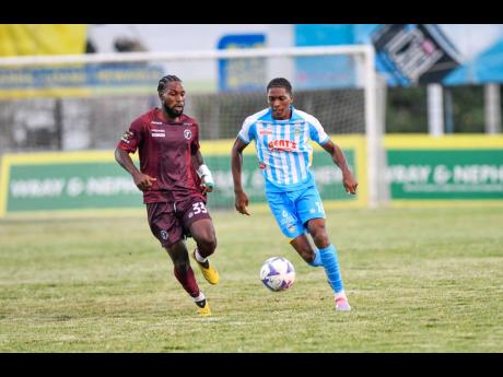 Chapelton Maroons’ Ajuma Johnson (left) chases Waterhouse’s Kymani Campbell during a Jamaica Premier League encounter at the Anthony Spaulding Sports Complex on Monday. The game ended in a 1-1 draw.