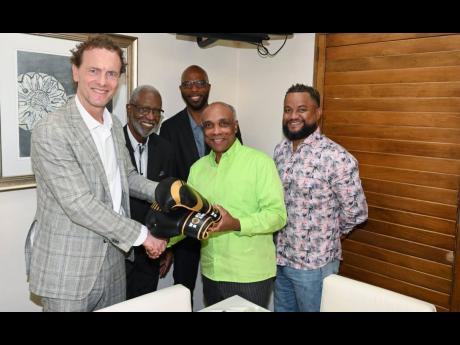 Credit: Contributed President of World Boxing Boris van der Vorst (left) and Christopher Samuda, Jamaica Olympic Association (JOA) president, are involved in a presentation of boxing gloves at a meeting where the JOA announced a $5m contribution toward a national boxing gym. Looking on are JBA representatives Keith Brown (second left), President Stephen Jones (centre), and Ryan Foster, JOA Secretary General/CEO.