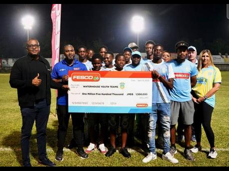 Jeremy Barnes (left), Fesco’s director and CEO, and Stefan Ebanks (second left), head of Business Development, Sales, Marketing and Communications, present their sponsorship commitment of $1.5 million to members of Waterhouse Football Club’s youth teams and management. Also present are club director Nicola Bicknell (right), Chairman Bruce Bicknell (second right, partly hidden) and Damoney Kildare, coach of the Under-13 and Under-15 teams.