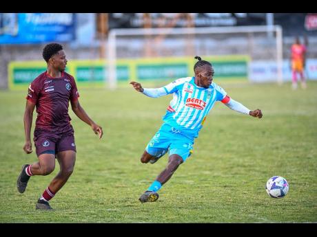 Credit: Matthew McKoy Andre Fletcher (right) of Waterhouse FC goes for a pass while Neumonie Blackwood of Chapelton Maroons FC looks on during their Jamaica Premier League football match at Anthony Spaulding Sports Complex in Kingston on Monday. Waterhouse will be looking to keep their top-six playoff spot in a matchup against Arnett Gardens on Sunday.