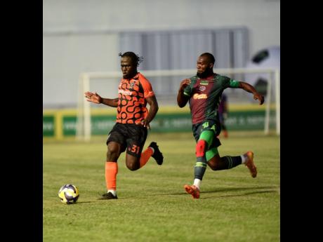 Alton Lewis (left) of Tivoli Gardens F.C. is pressured for the ball by Owayne Gordon of Montego Bay United during their Jamaica Premier League (JPL) football quarter-final match at Sabina Park on Thursday. MoBay United won 2-1.