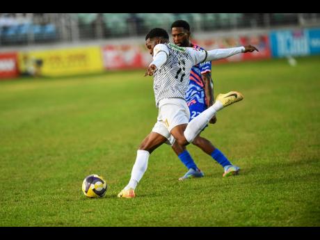 Chrtostopher Ainsworth (left) of Cavalier FC prepares to kick the ball as he comes under pressure from Ronaldo Robinson of Portmore United FC during their Jamaica Premier League quarter-final football match at Sabina Park, Kingston, on Monday.