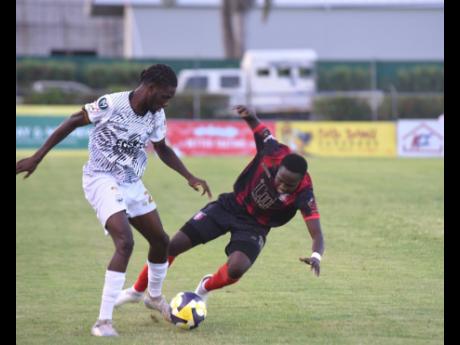 Cavalier FC’s Jerome McLeary (left) battles for the ball with Arnett Gardens FC’s Jahiem Thomas during their Jamaica Premier League first-leg semi-final football match at the Montego Bay Sports Complex, St James, on Thursday night.