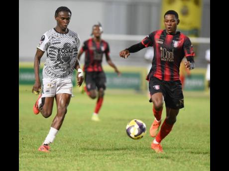 Credit: Ian Allen Cavalier’s Jalmaro Calvin (left) and Philando Wing of Arnett Gardens compete for the ball during their Jamaica Premier League football semi-final at Sabina Park on Sunday.