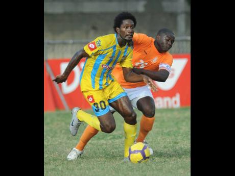 Credit: Ian Allen File photo shows Waterhouse’s Hugh Howell (left) dribbling under pressure from Benfica’s captain Andrew Dixon during a Premier League football encounter at the Waterhouse Mini-Stadium in 2011. Waterhouse won 4-0.