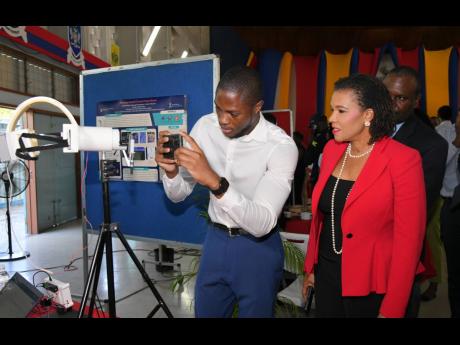 Credit: Contributed Minister without Portfolio in the Office of the Prime Minister with responsibility for Efficiency, Innovation, and Digital Transformation, Senator Ambassador Audrey Marks, observes as engineering student, Ricardo Harrison, explains his project, titled ‘Diabetic Retinopathy Using Computer Vision’, during the recent inaugural Mona Engineering Project Expo, held at The University of the West Indies, Mona, in St Andrew.