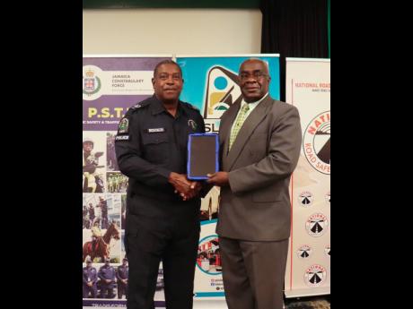 Credit: Contributed Director General of Road Traffic at the Island Traffic Authority, Colonel Daniel Pryce (right), presents a tablet computer to Head of the Jamaica Constabulary Force’s Public Safety and Traffic Enforcement Branch, Assistant Commissioner of Police Dr Gary McKenzie, during the recent National Road Safety Council meeting at the Courtleigh Hotel & Suites in Kingston.
