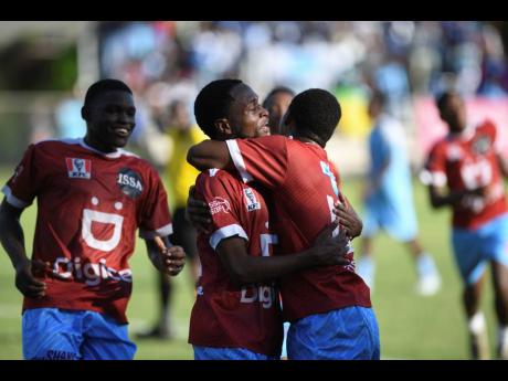 Timothy Jones (centre)  of St Catherine High is embraced by his teammate Tevin Grey after he scored during a Manning Cup match against St George’s College on October 18, 2024 at Winchester Park. 