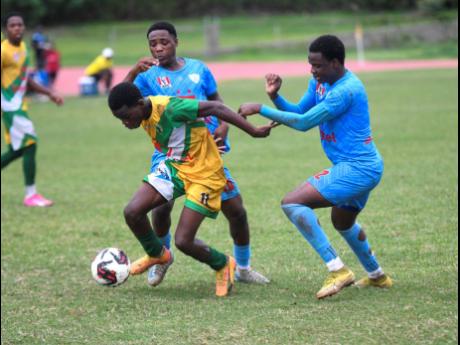 Kivan Salmon of Excelsior High School (front) shields the ball from St Catherine  High’s  Kadean Young (back left) and Damari Henry during a Manning Cup match at the Stadium East field on November 16, 2024.