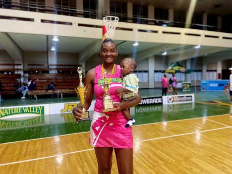 Credit: Sharla Williams KIngston Hummingbirds’ Tracyann Francis holds her nine-year-old son while displaying trophies earned for her outstanding performance in Netball Jamaica’s Red Stripe Flavours Netball Netball, following Sunday’s final inside the National Arena.