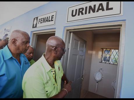 Credit: Ian Allen Desmond McKenzie (right), minister of local government and community development and Franklin Witter (left), member of parliament for St Elizabeth South Eastern, inspect one of the urinals at the new sanitary facility in Junction, St Elizabeth, on Thursday.