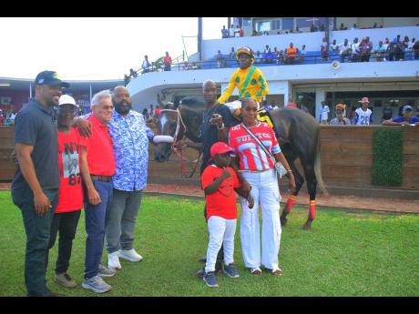 Supreme Ventures Racing and Entertainment Limited’s chairman Solomon Sharpe (fourth left) hugs winning trainer Philip Feanny, while RIDEALLDAY, with jockey Paul Francis in the saddle, parades in the winners enclosure with connections following the running of the Pootlittlerichgirl Trophy event, over 7 1/2 furlongs, at Caymanas Park on Saturday.