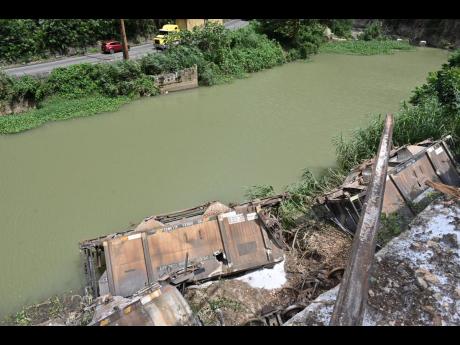The derailed cars from the bauxite train that nearly ended up fully in the Rio Cobre.