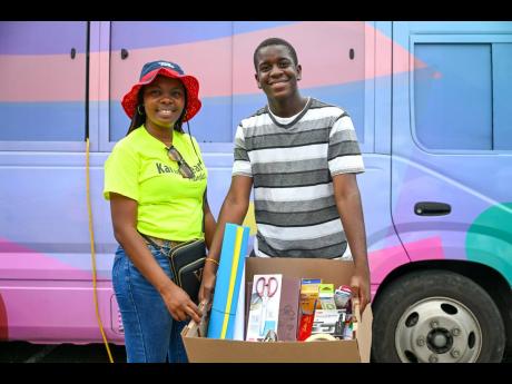 Founder of the Karing Hearts Foundation, Kayann Wallace (left), receives school supplies from Ricardo Buckley, community peer educator and deputy youth mayor.