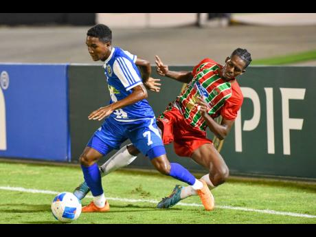 Credit: Matthew McKoy Devonte Campbell (left) of Mount Pleasant turns away from Allierio Belfor of Robinhood FC during their Concacaf Caribbean Cup match at the National Stadium last night.