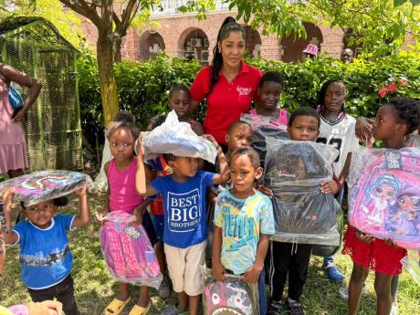 Credit: Contributed Above: Dancehall artiste D’Angel with some of the children who were fêted at the back-to-school treat in Spanish Town.