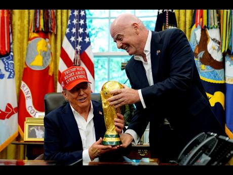 FIFA President Gianni Infantino (right) hands the FIFA World Cup to President Donald Trump during an announcement in the Oval Office of the White House on Friday, August 22, 2025, in Washington.
