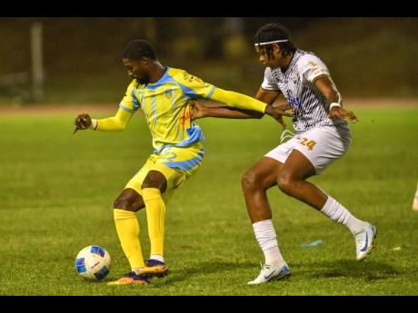 Credit: Matthew McKoy Colorado Murray (left) of Waterhouse FC shields the ball from Michael Forbes of Cavalier Soccer Club during the Jamaica Premier League football match at Stadium East, Kingston, yesterday. Waterhouse won 1-0.