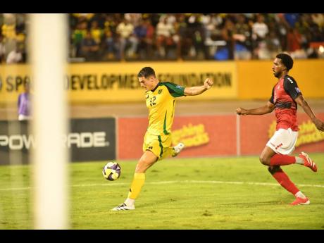 Credit: Matthew McKoy Jamaica’s 20-year-old forward Bailey Cadamarteri (left) shoots to score the opening goal during last night’s Concacaf World Cup Group B qualifying match against Trinidad and Tobago at the National Stadium. Jamaica won 2-0.