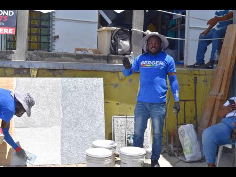 Credit: Contributed Contractor Everol Thompson (right) walks attendees through a live demo being conducted by his colleague Seyan Grant (left) during the Berger Paints Jamaica’s Trowel-On Roadshow at Paint Up Hardware, Westmoreland.