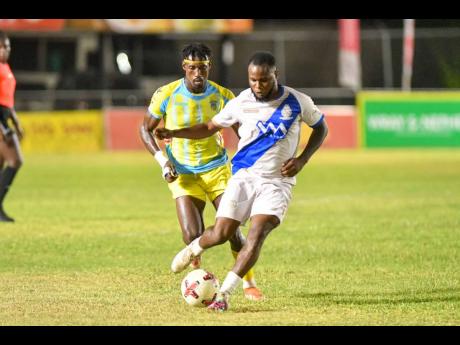 Credit: Matthew McKoy Trayvone Reid of Harbour View FC kicks the ball before Waterhouse FC’s Javane Bryan is able to make a tackle during the Jamaica Premier League football match at Drewsland Mini-Stadium in St Andrew yesterday. Harbour View won 2-1.